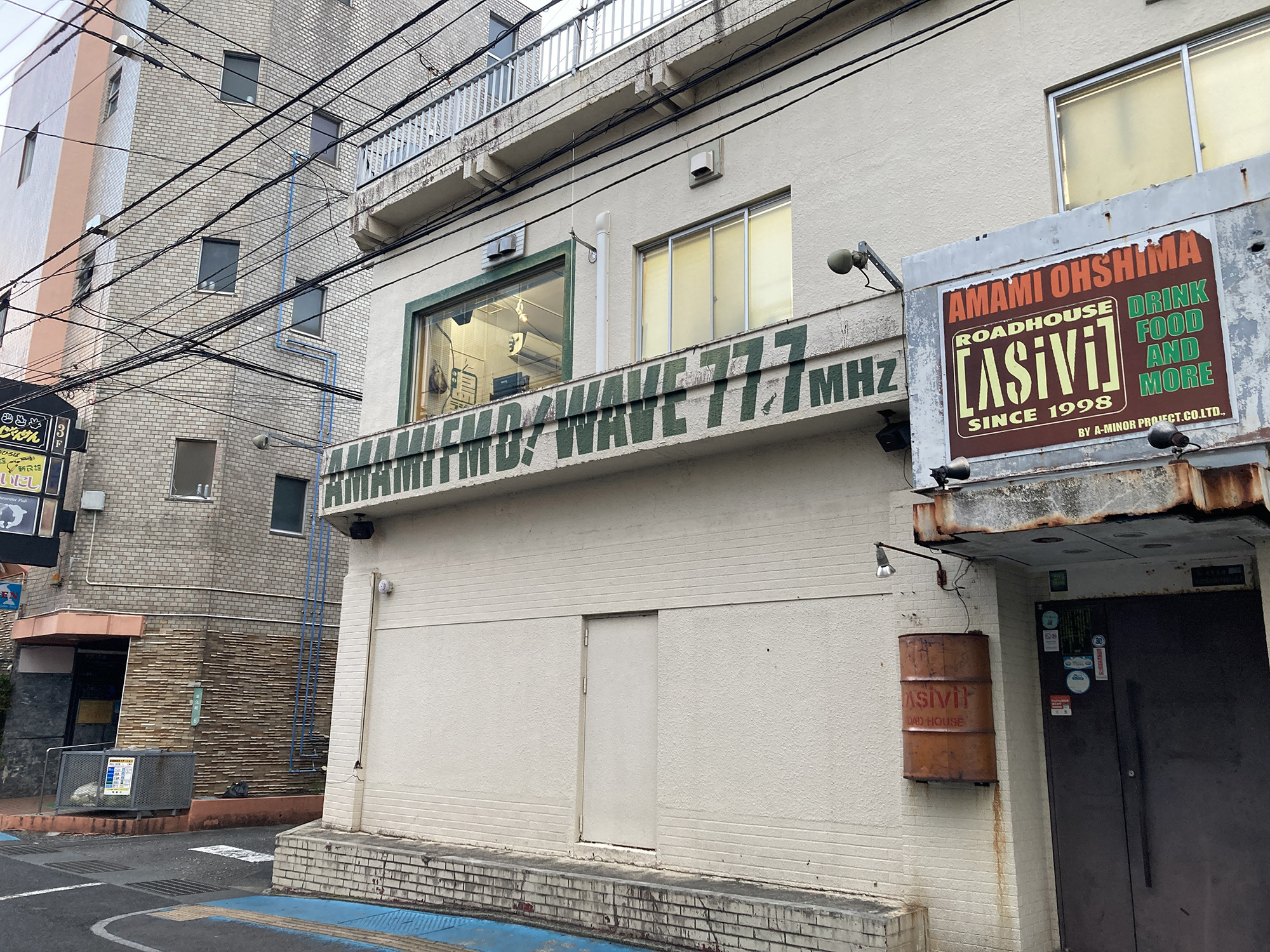 「アシビ」と「あまみエフエム」の入る建物の引きの外観写真。